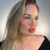 Woman with blonde hair and black top against a plain background plastic surgery lip filler cheek filler