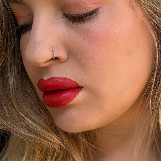 Close-up of a woman's face with red lipstick and blonde hair. lip filler. lip prosthetic