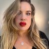 Woman with long blonde hair and red lipstick wearing a black top. lip filler. lip prosthetic