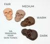 Skull-shaped prosthetics in different skin tone shades on a white background.