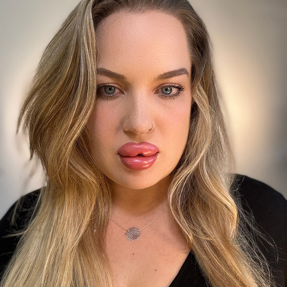 Woman with long blonde hair and pink lipstick against a neutral background