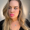 Woman with long blonde hair and pink lipstick wearing a black top against a neutral background. lip filler prosthetic