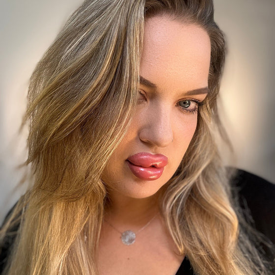 Woman with long blonde hair and pink lipstick against a neutral background