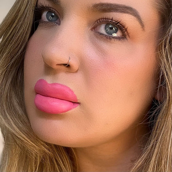 Close-up of a woman's face with pink lipstick and blonde hair. lip filler. lip prosthetic