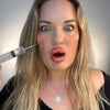 Person holding a syringe near their face with a neutral background plastic surgery lip filler cheek filler